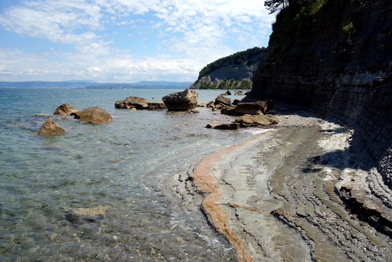 Formazioni rocciose striate di rosso lungo la costa tra la spiaggia di Strugnano e Mesečev Zaliv, la Baia della Luna.